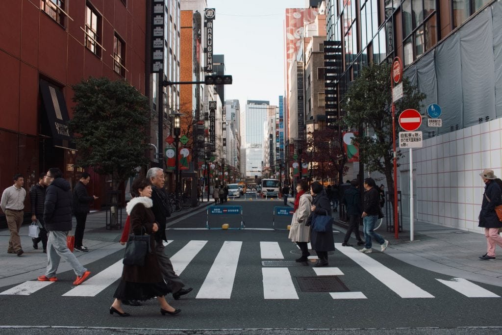 mehrere Menschen gehen über einen Zebrastreifen in den Straßen von Tokio