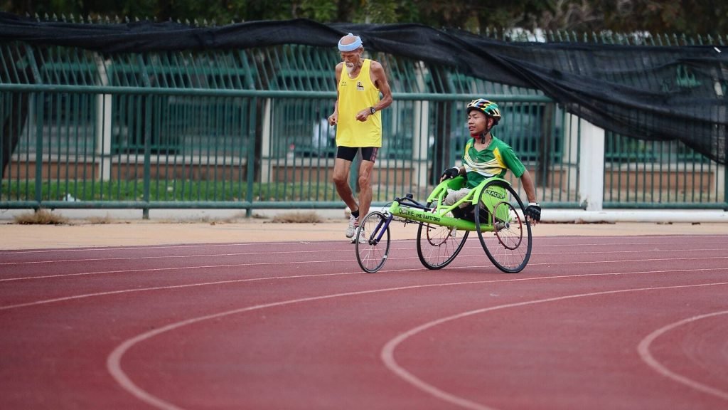 Das Bild zeigt einen Mann, der auf einer Laufbahn in einem Rollstuhl Sport treibt.