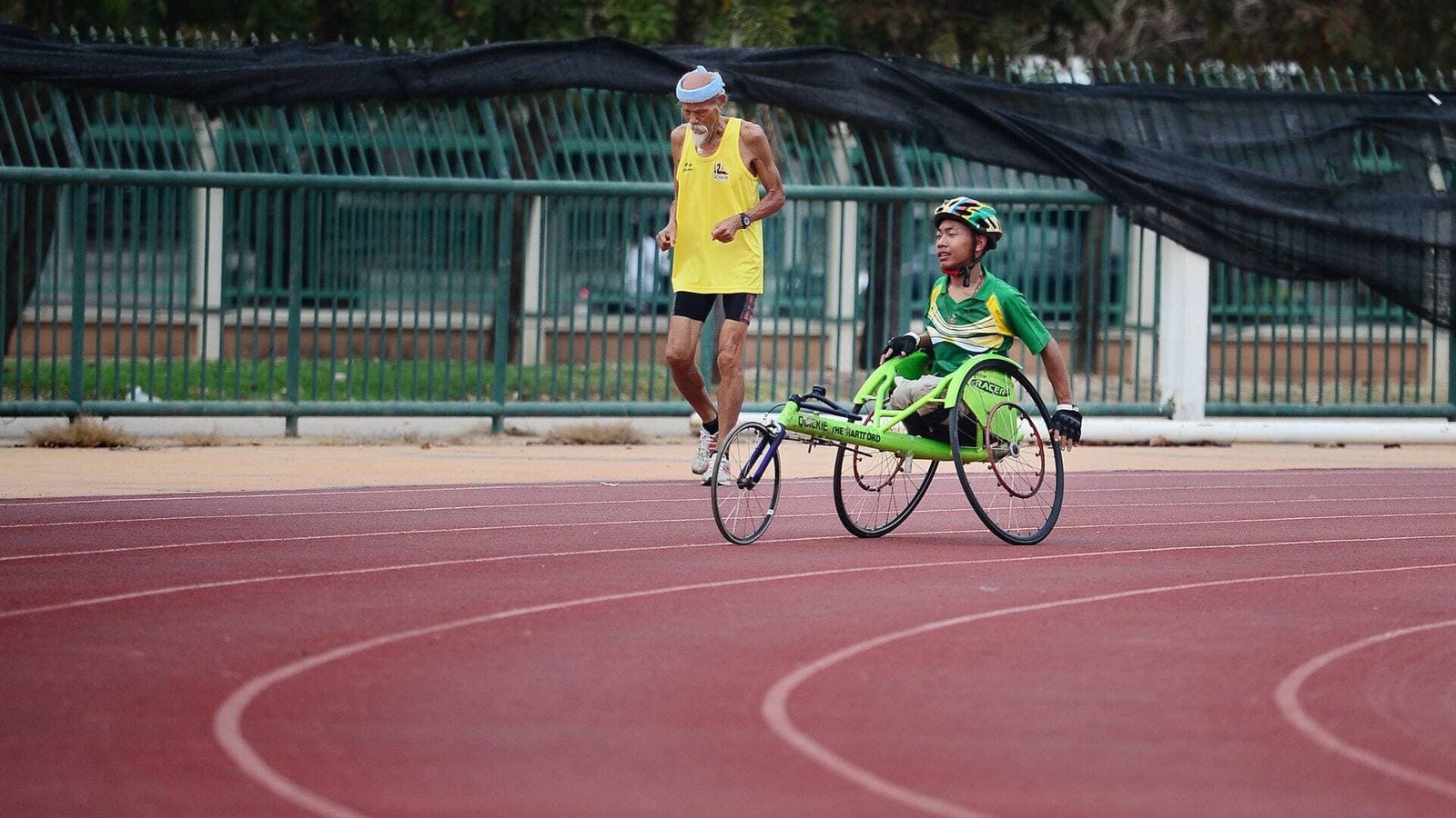 Das Bild zeigt einen Mann, der auf einer Laufbahn in einem Rollstuhl Sport treibt.