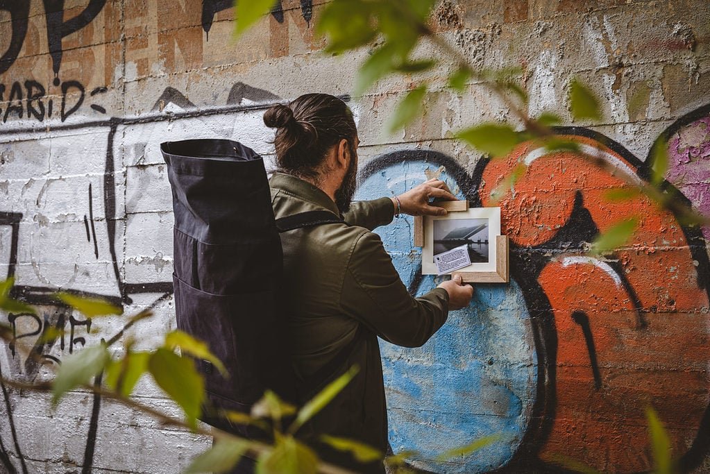 Paul von Framespotting hängt ein Bild an einer Wand auf.