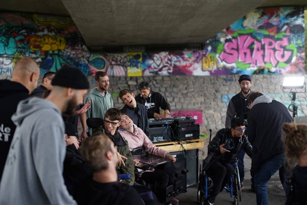 Verschiedene Menschen mit und ohne körperliche Einschränkungen beim Musikvideodreh