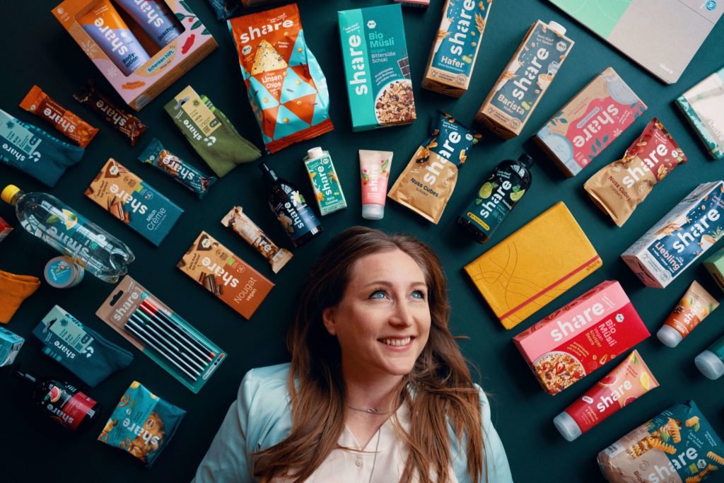 Iris Braun mit verschiedenen share-Produkten platziert um ihren Kopf. Foto: Max Threlfall