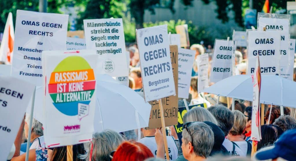 Menschen bei einer Demo und Plakate mit verschiedenen Aufschriften. Darunter mehrfach "Omas gegen Rechts".