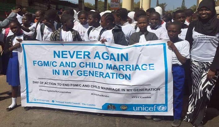 Menschen halten zusammen ein Schild von Unicef mit der Aufschrift: "Never again FGM/C and child marriage in my generation"