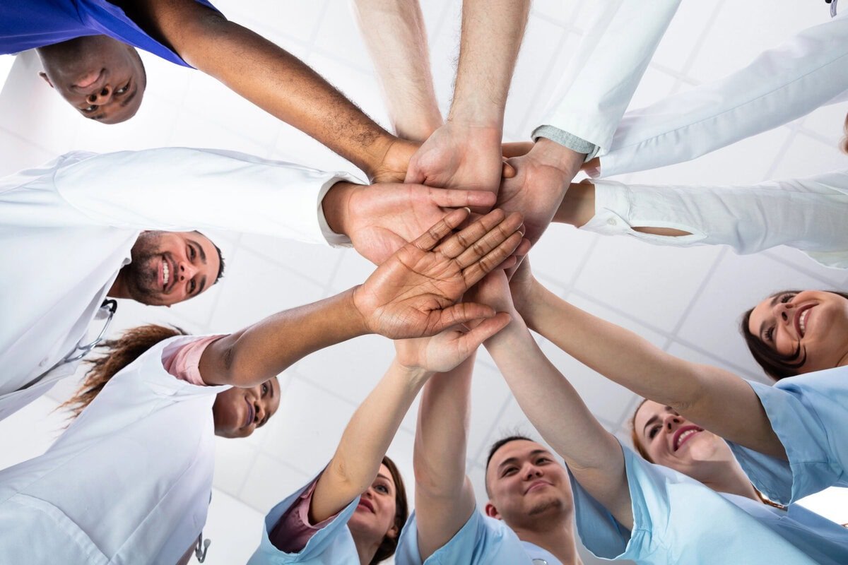 Alle gemeinsam für Gesundheit in der Welt - https://depositphotos.com/de/photo/low-angle-view-doctor-stacking-hands-together-hospital-271589100.html