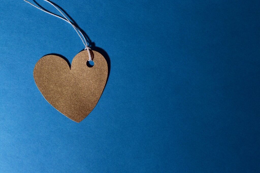 Ein goldenes Herz hängt an einer Schnur vor einem blauen Hintergrund, symbolisiert Liebe und positive Nachrichten.