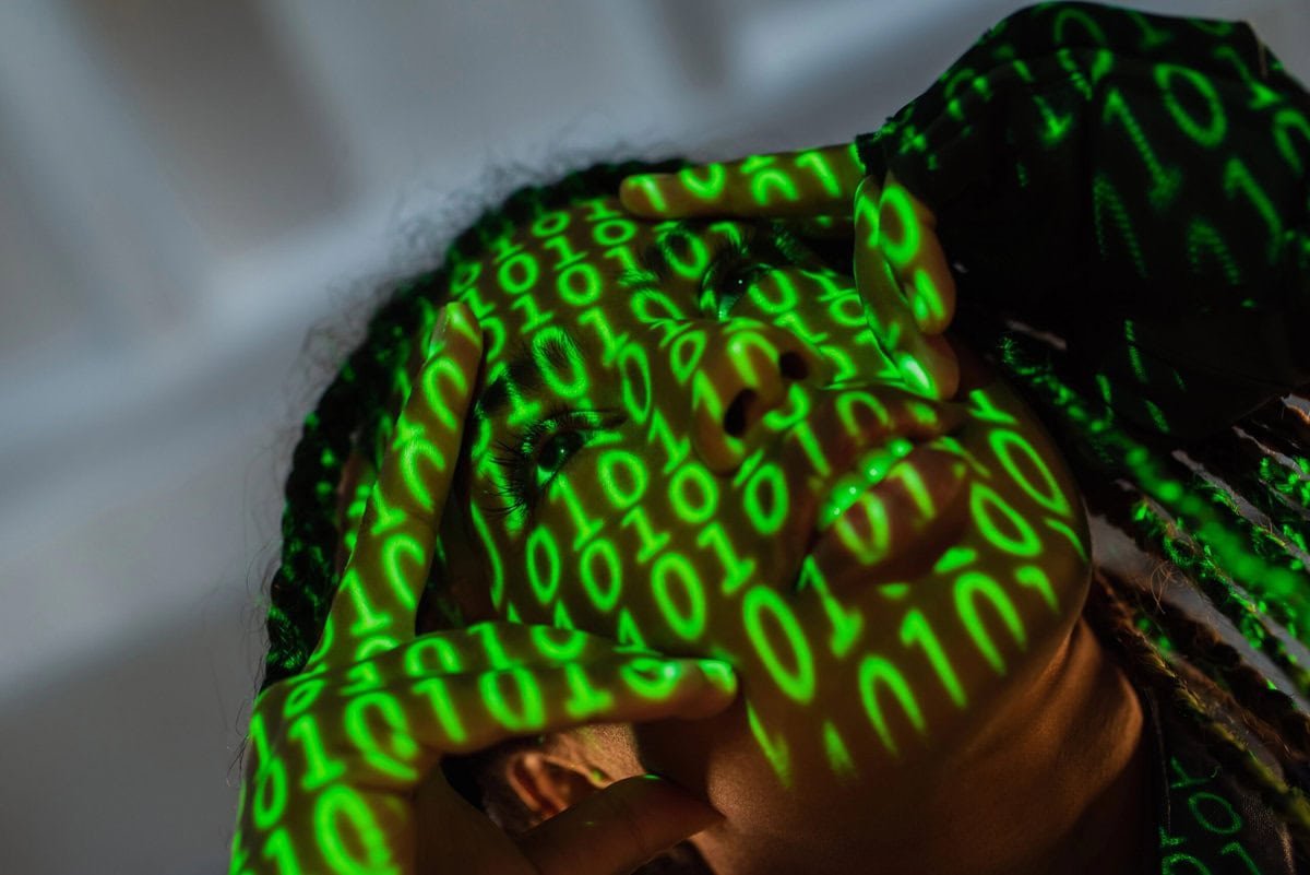Deepfakes werden in UK bestraft - Bild: https://depositphotos.com/de/photo/low-angle-view-african-american-woman-projection-binary-code-touching-574045042.html